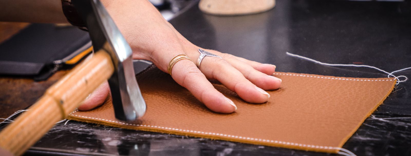 Artisan maroquinier au travail sur une pièce de cuir à la Maroquinerie du Puy